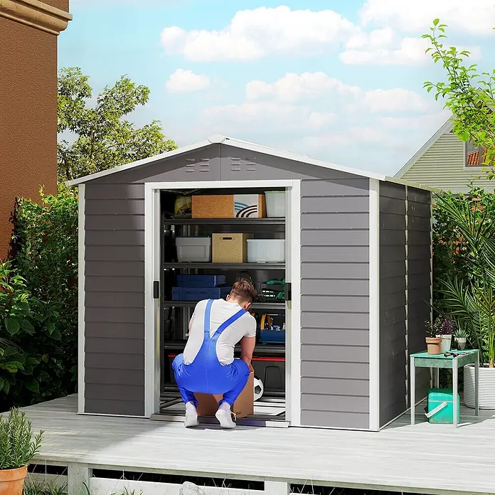 Outsunny Gerätehaus - Außenbreite inkl. Dachüberstand: 240 cm, Außentiefe inkl. Dachüberstand: 206 cm, Stahl, Hellgrau - Ein geräumiger grau-weißer Geräteschuppen auf einer Holzterrasse, mit Regalen organisiert und von einer Person als Stauraum genutzt.