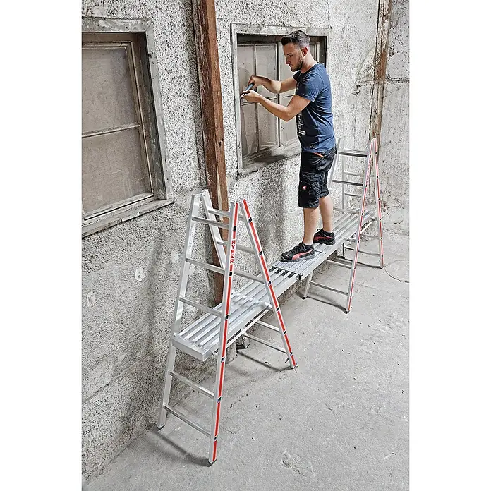 Hymer Arbeitsplattform Alu-Teleskop-Diele 1,79-2,9m Länge - Aluminium - Mann auf einer silbernen Aluminium-Arbeitsplattform mit roten Akzenten, der an einem Fenster arbeitet.
