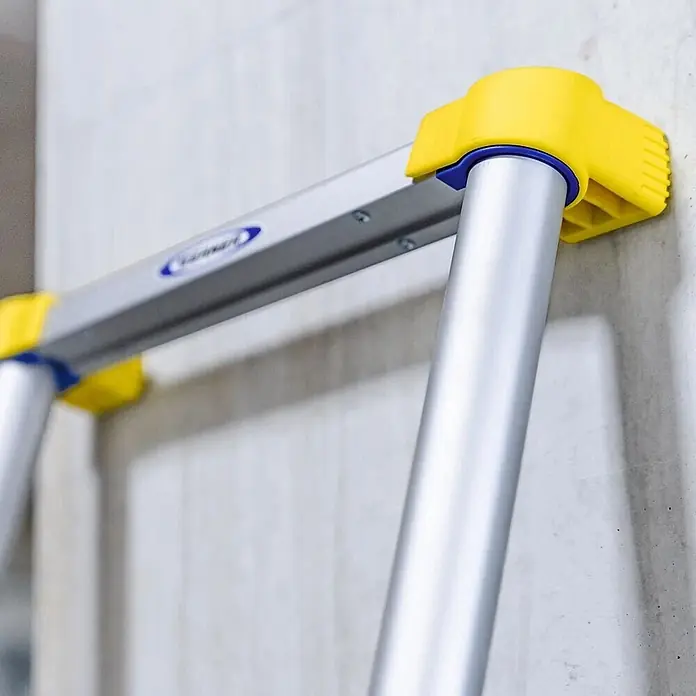 Werner Anlegeleiter Teleskop Anlegeleiter 2,90m - Anzahl Tritte: 10 Stk., Arbeitshöhe: 3.670 m, Aluminium - Nahaufnahme einer silbernen Aluminiumleiter mit gelben Endkappen und blauen Akzenten, die an einer Wand lehnt.