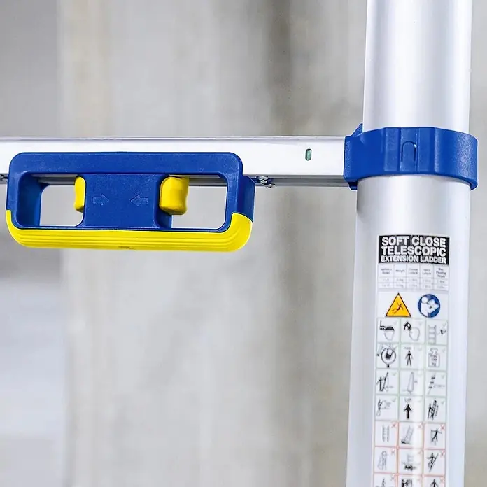 Werner Anlegeleiter Teleskop Anlegeleiter 2,90m - Anzahl Tritte: 10 Stk., Arbeitshöhe: 3.670 m, Aluminium - Blau-gelber Sanftschließmechanismus einer Teleskopleiter mit Sicherheitsetiketten am silbernen Holm.