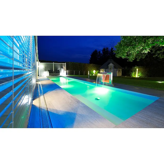 Ideal Eichenwald Pooldusche Modell 52 Schwalldusche Aquarius mit RGB-Beleuchtung - Edelstahl - Moderner Außenpool bei Nacht, beleuchtet mit leuchtend grünem Wasser und einem farbigen Wasserfall. Sanfte Beleuchtung hebt die elegante Terrasse und den Garten hervor.