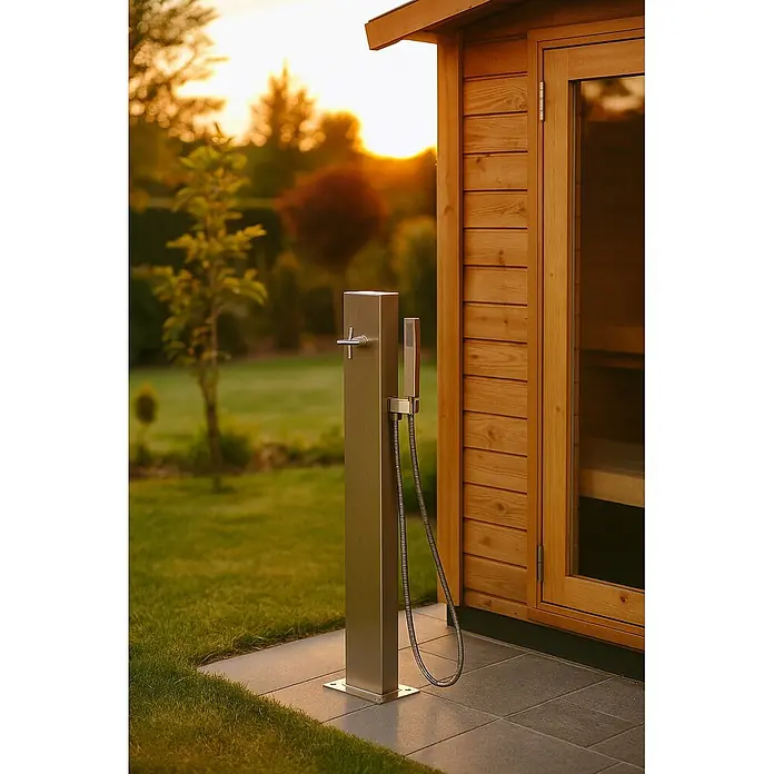 Ideal Eichenwald Pooldusche Modell 40.1 Gartendusche Madeira Typ Mischbatterie - Edelstahl - Außendusche aus gebürstetem Metall mit Handbrause, auf Terrassenfliesen neben einer Holzsauna, im warmen Sonnenuntergangslicht.