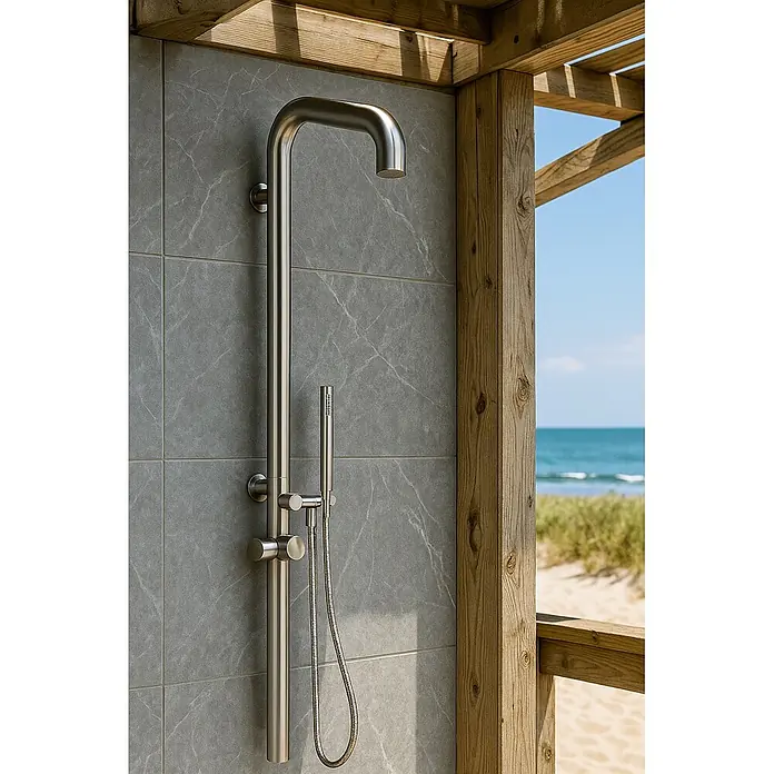Ideal Eichenwald Pooldusche Modell 70 Gartendusche Sylt Wandmontiert - Höhe: 0,01 m, Edelstahl - Outdoor-Duschsäule aus gebürstetem Edelstahl mit Kopf- & Handbrause, an grauen Fliesen unter Holzgerüst am Sandstrand mit Meer.