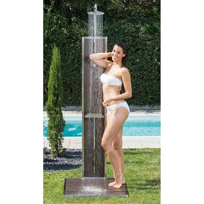 Ideal Eichenwald Pooldusche Modell 70 Gartendusche Bahama mit Bodenplatte - Edelstahl - Stilvolle Außendusche aus Holz und Metall, von einer Frau am Pool im Garten genutzt.