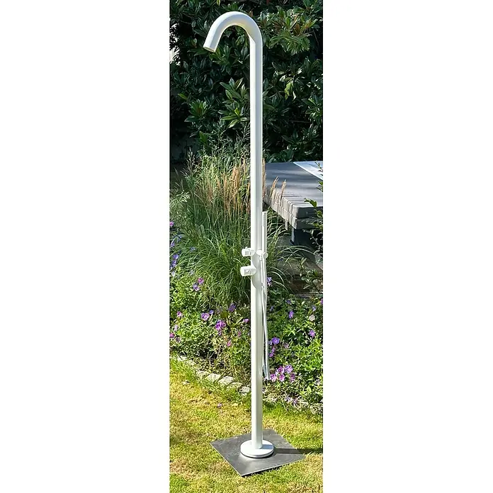 Ideal Eichenwald Pooldusche Modell 70 Gartendusche Sylt in Weiß - Edelstahl - Weiße Außendusche mit Handbrause und gebogenem Kopf, in einem Garten mit Pflanzen und Blumen.