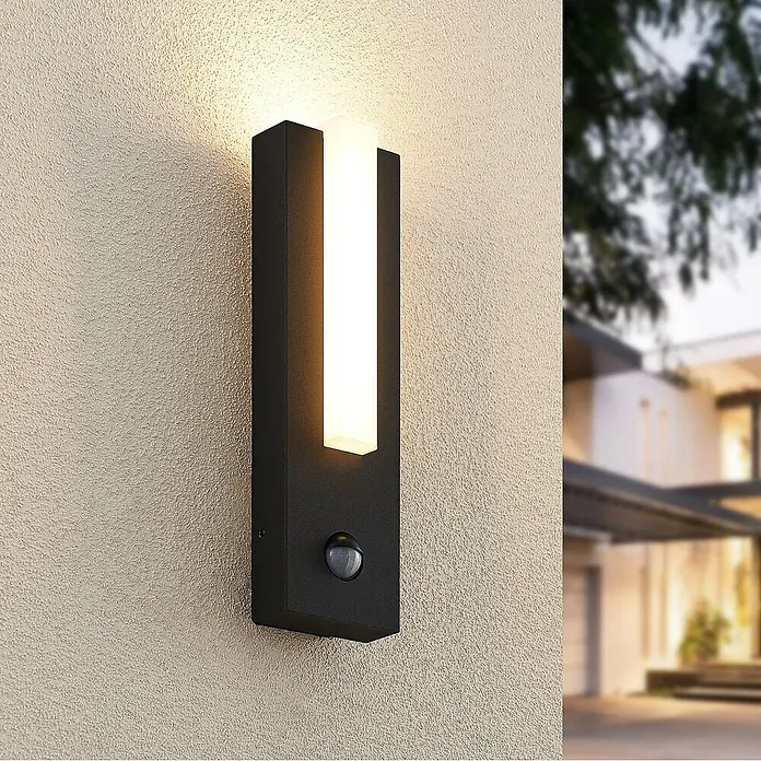 Lucande Außenwandleuchte Virgalia - schwarz, IP54 - Schwarze, rechteckige Außenwandleuchte mit weißem Lichtstreifen und integriertem Bewegungssensor, an einer strukturierten Wand montiert.