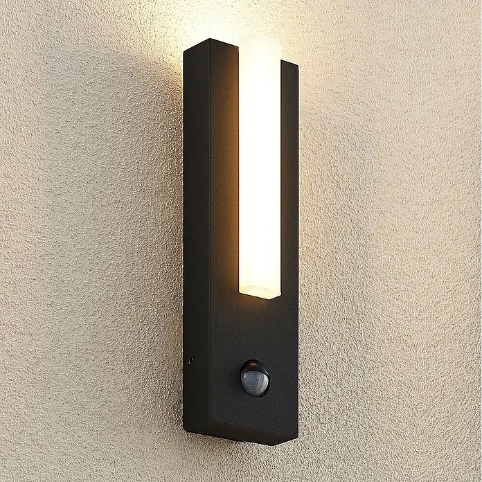 Lucande Außenwandleuchte Virgalia - schwarz, IP54 - Schwarze, rechteckige Außenwandleuchte mit beleuchtetem weißen Streifen und integriertem Bewegungsmelder an einer texturierten Wand.