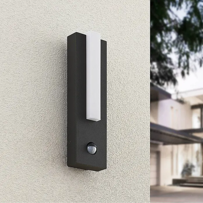 Lucande Außenwandleuchte Virgalia - schwarz, IP54 - Dunkelgraue Außenwandleuchte mit weißem LED-Streifen und Bewegungssensor, an strukturierter Wand montiert.