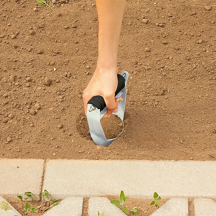 Gardol Plantador para bulbos - 80 mm, Negro/Plateado - Herramienta de jardinería en acción: una persona usa una herramienta manual para quitar las malas hierbas y cuidar el jardín.