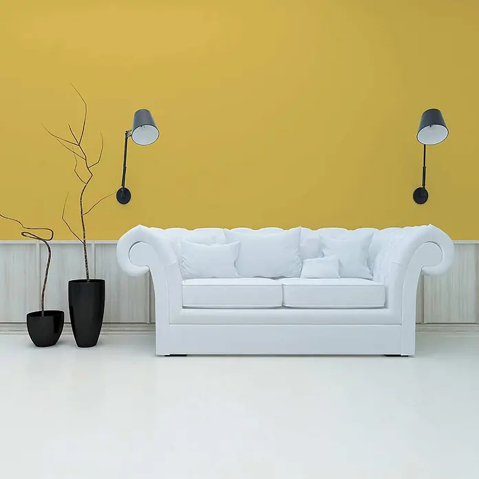 Tadessi Wandfarbe Sonnenocker - Gelb, Matt, 5 l - Weißes getuftetes Sofa mit Kissen in einem modernen Wohnzimmer mit gelber Wand.
