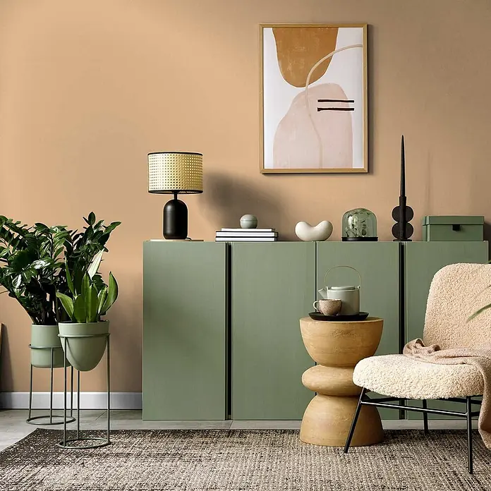 Tadessi Wandfarbe Kamelbraun - Beige, Matt, 5 l - Ein mattgrüner Aufbewahrungsschrank, mit Dekoartikeln inszeniert, prägt eine wohnliche Szene.