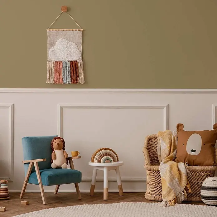 Tadessi Wandfarbe Olivbeige - Grün, Matt, 2,5 l - Blauer Samtsessel, Korbsessel mit Bärenkissen, kleiner weißer Tisch mit Regenbogenspielzeug und Wolken-Wandbehang in einem Kinderzimmer.
