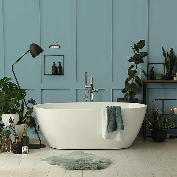 Tadessi Wandfarbe Laugenblau - Blau, Matt, 1 l - Weiße freistehende Badewanne in einem modernen Badezimmer mit blauen Wänden und Pflanzen.