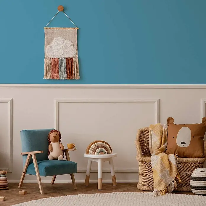 Tadessi Wandfarbe Azurblau - Blau, Matt, 2,5 l - Gemütliche Kinderecke mit blauer Wand. Eine Wolken-Regenbogen-Wandbehang, ein blauer Samtstuhl mit Igel-Stofftier und ein Korbsessel mit Bärenkissen.