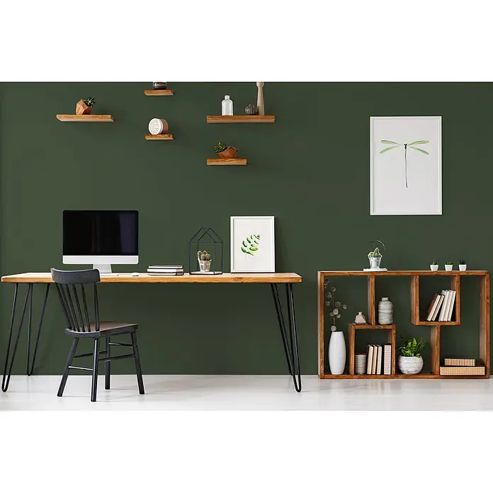 Tadessi Wandfarbe Sage Green - Grün, Matt, 5 l - Ein modernes Heimbüro mit hellem Holzschreibtisch, schwarzem Stuhl und hölzernem Würfelregal, dekoriert mit Pflanzen und Büchern.