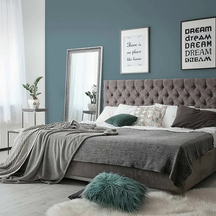 Tadessi Wandfarbe Mokka - Blau, Matt, 5 l - Modernes Schlafzimmer mit grauem gepolstertem Bett, grauer Bettwäsche und einem türkisen Zierkissen.