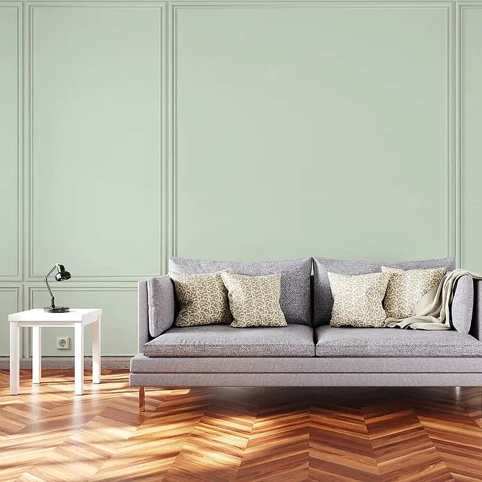 Tadessi Wandfarbe Minzgrün - Grün, Matt, 5 l - Grau gepolstertes Sofa mit beigefarbenen Zierkissen und einer passenden Decke in einem Wohnzimmer.