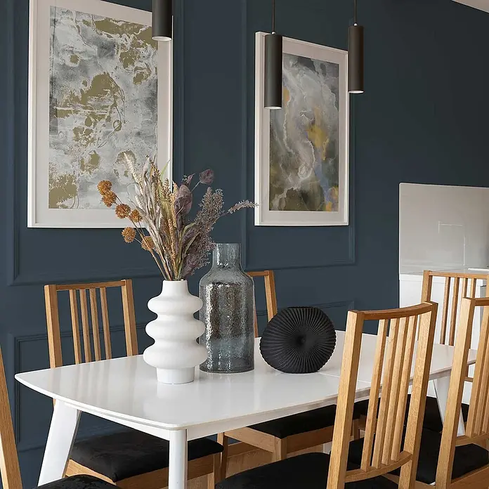 Tadessi Wandfarbe Taupe - Blau, Matt, 2,5 l - Moderner weißer Esstisch und Holzstühle mit schwarzen Sitzen in einem stilvollen Esszimmer.