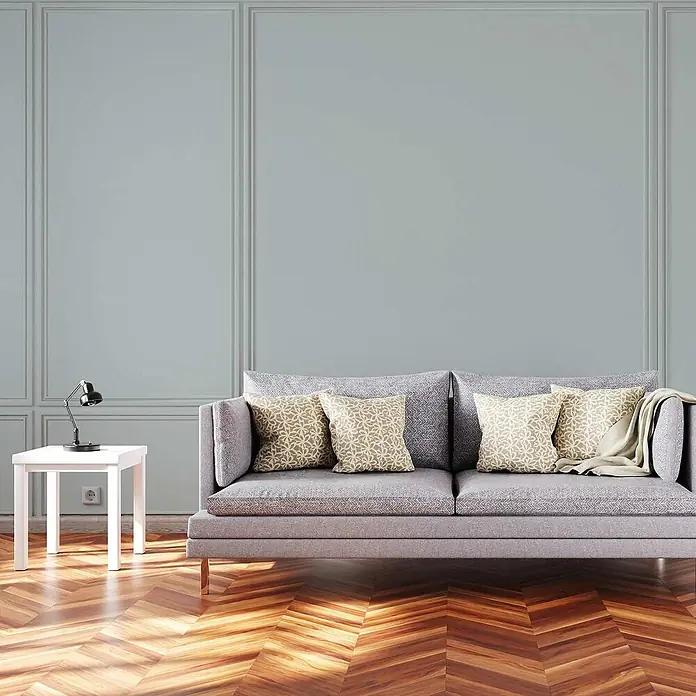 Tadessi Wandfarbe Toffee - Blau, Matt, 5 l - Ein modernes hellgraues Sofa mit vier gemusterten Kissen und einer hellen Decke für ein gemütliches Wohnzimmer.