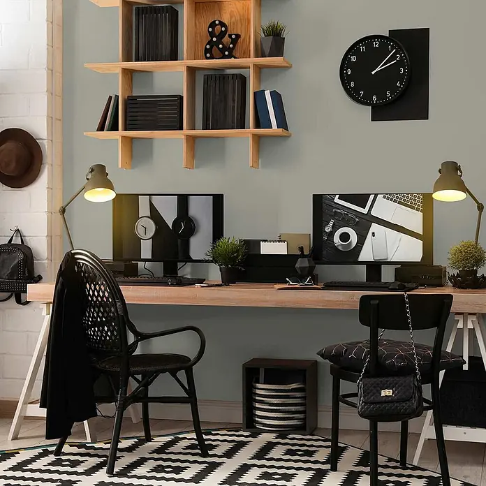 Tadessi Wandfarbe Moosgrau - Grau, Matt, 1 l - Ein modernes Heimbüro mit hellem Holzschreibtisch, zwei schwarzen Stühlen, zwei Monitoren und einem Wandregal aus Holz.