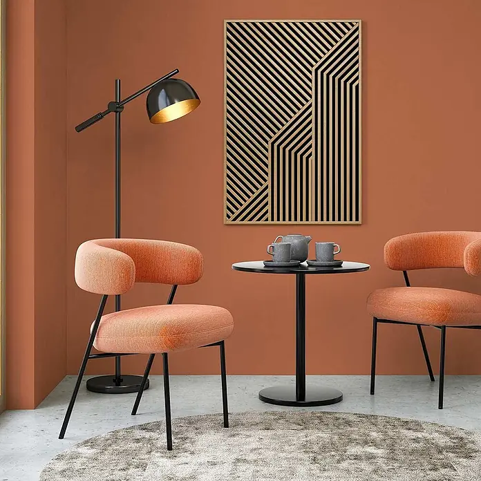Tadessi Wandfarbe Sonnengelb - Rot, Matt, 1 l - Moderne, orange gepolsterte Loungesessel mit schwarzen Beinen, die einen schwarzen runden Beistelltisch flankieren.
