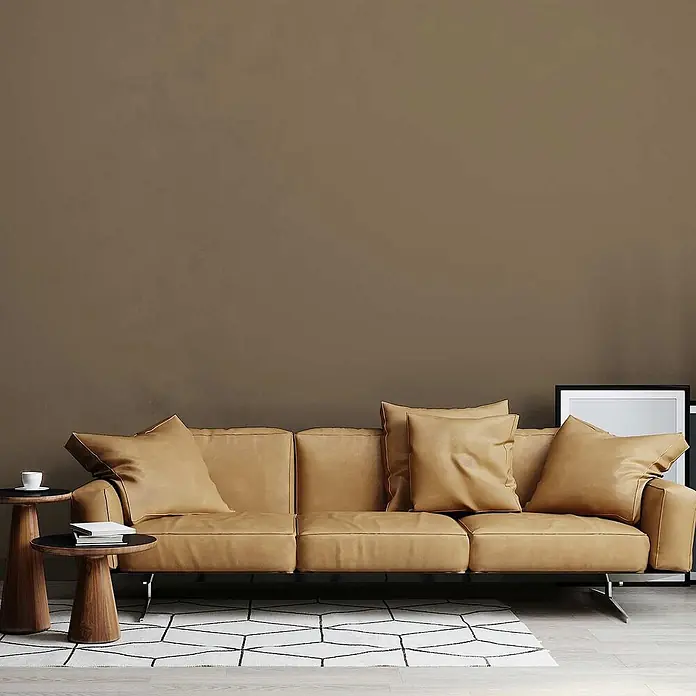 Tadessi Wandfarbe Mandelbraun - Braun, Matt, 1 l - Helles braunes Ledersofa mit Kissen, Holztischen und einem gemusterten Teppich in einem modernen Wohnzimmer.