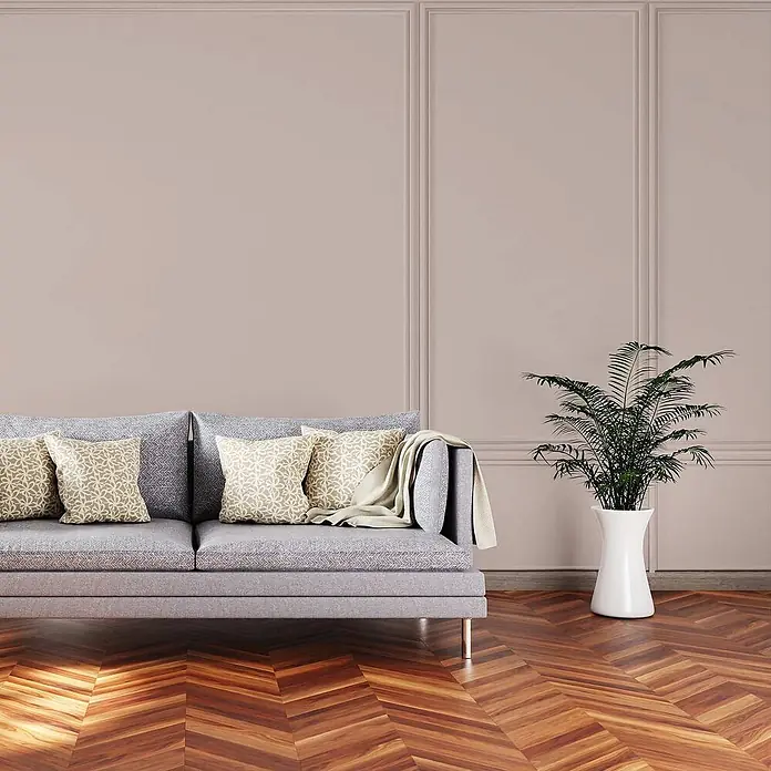 Tadessi Wandfarbe Kupferrot - Beige, Matt, 1 l - Modernes graues Stoffsofa mit gemusterten Kissen und einer Decke in einem modernen Wohnzimmer.