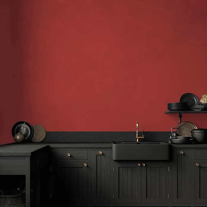 Tadessi Wandfarbe Granatapfelrot - Rot, Matt, 1 l - Dunkle Küchenschränke mit schwarzem Spülbecken und Messingarmatur vor einer lebhaften roten Wand.