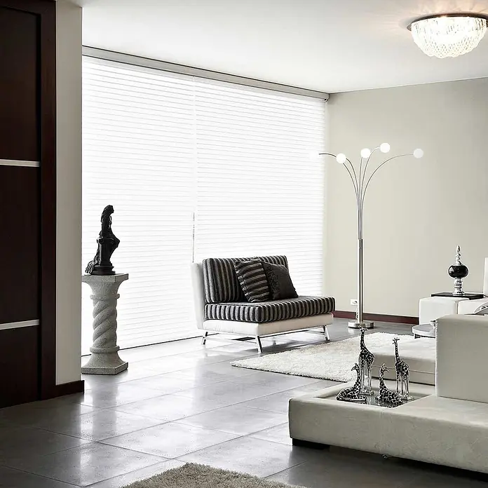 Tadessi Wandfarbe Graugrün - Creme, Matt, 2,5 l - Modernes Wohnzimmer mit gestreiftem Sofa, weißem Sektionssofa, moderner Stehlampe und eleganten weißen Jalousien.