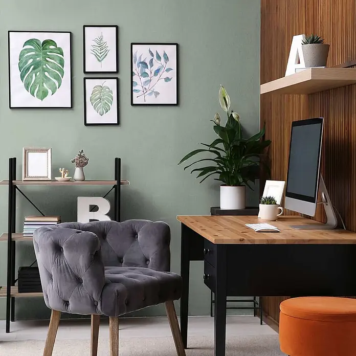 Tadessi Wandfarbe Flamingo - Grün, Matt, 2,5 l - Modernes Home Office mit hellem Holz- und schwarzem Schreibtisch, grauem Samt-Sessel und rundem orangem Samt-Hocker.