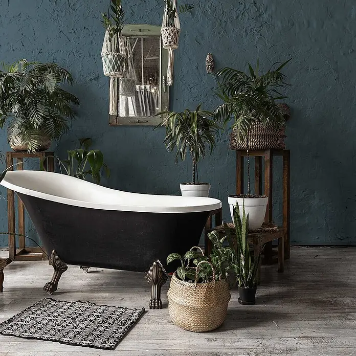 Tadessi Wandfarbe Kaltblau - Blau, Matt, 5 l - Schwarz-weiße Klauenfußwanne in einem botanischen Badezimmerambiente, umgeben von grünen Pflanzen.