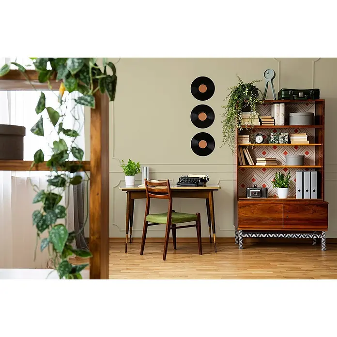 Tadessi Wandfarbe Vanillegrün - Grün, Matt, 2,5 l - Ein Arbeitszimmer im Vintage-Stil mit einem Holzschreibtisch, einem Stuhl mit grüner Polsterung und einem großen Bücherregal voller Gegenstände und Pflanzen.