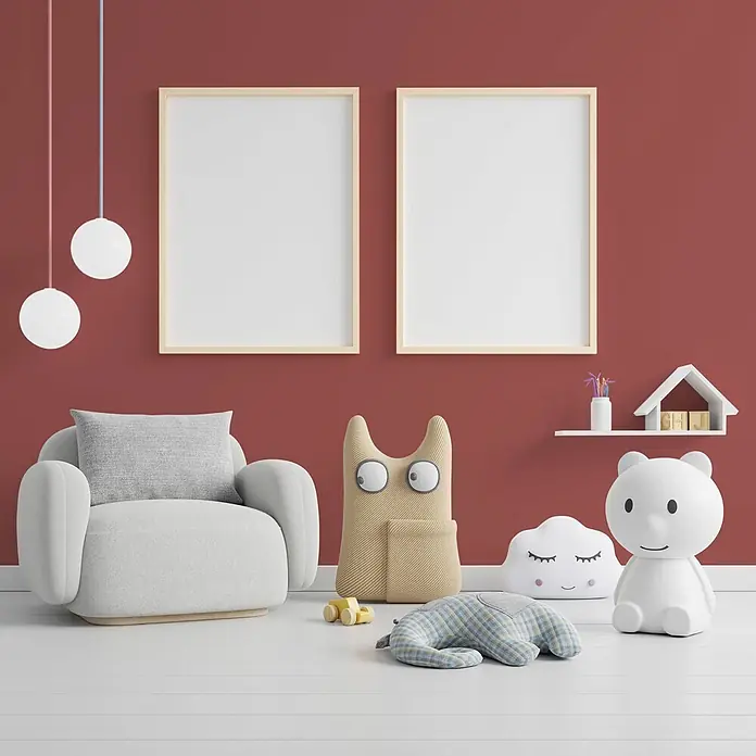 Tadessi Wandfarbe Seidengold - Rot, Matt, 5 l - Ein farbenfrohes Kinderzimmer mit roter Wand, grauem Sessel, leeren Rahmen, Hängelampen und Spielzeug.