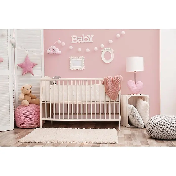 Tadessi Wandfarbe Blütenrosa - Rosa, Matt, 5 l - Ein rosa Babyzimmer mit weißem Babybett, Teddybär und festlichen Dekorationen.