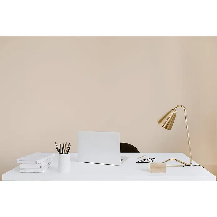 Tadessi Wandfarbe Haferbeige - Beige, Matt, 5 l - Minimalistischer weißer Schreibtisch mit Laptop, Büchern, Stiften und goldener Schreibtischlampe.