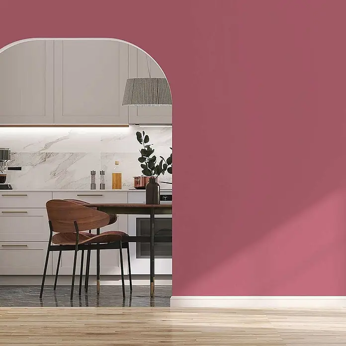 Tadessi Wandfarbe Eisrosa - Pink, Matt, 5 l - Eine moderne Küche mit hellem Durchgang, sichtbar von einem Raum mit kräftiger rosafarbener Wand und Holzfußboden.