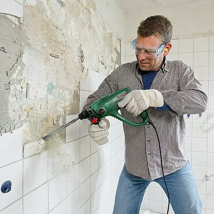 Bosch Martillo combinado PBH 2200 RE - 570 W, 1,8 J, Alojamiento SDS-Plus - Hombre usa un taladro percutor Bosch verde para quitar azulejos de una pared.