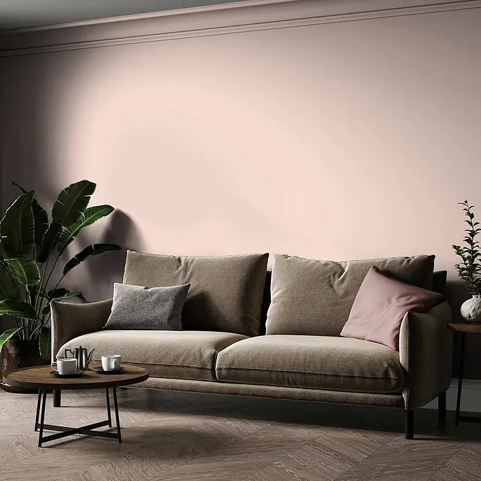 Tadessi Wandfarbe Lehm - Rosa, Matt, 1 l - Ein bequemes, neutral getöntes Stoffsofa in einem modernen Wohnzimmer mit hellrosa Wand und Pflanzen.