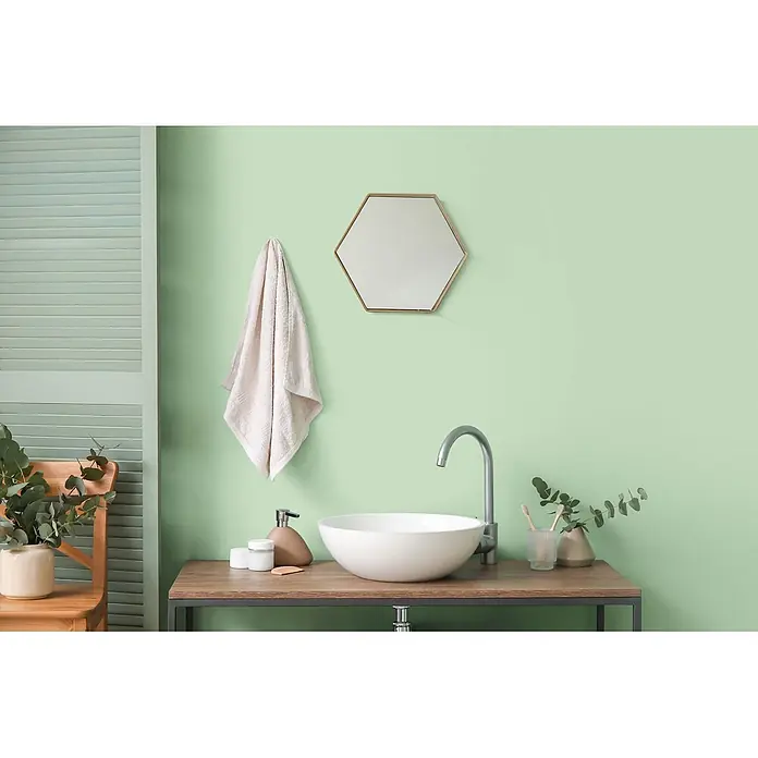 Tadessi Wandfarbe Limette Sage Green - Grün, Matt, 2,5 l - Moderner Badschrank mit weißem Waschbecken, silbernem Wasserhahn und Holzplatte mit dunklem Rahmen.