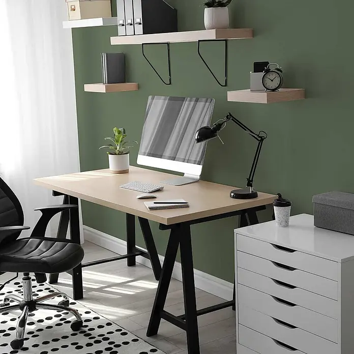 Tadessi Wandfarbe Avocadogrün - Grün, Matt, 5 l - Modernes Home-Office mit hellem Holzschreibtisch, schwarzem ergonomischen Stuhl und weißer Schubladeneinheit, für Produktivität eingerichtet.