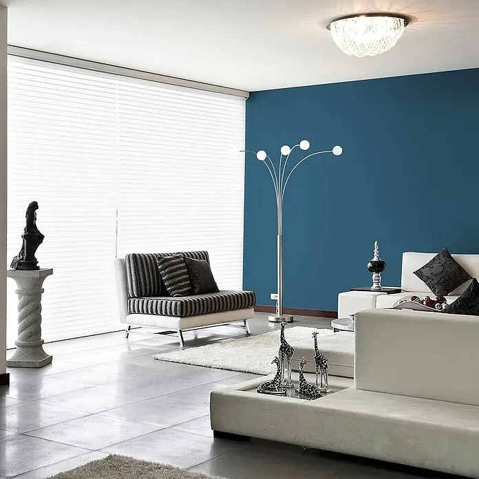 Tadessi Wandfarbe Marineblau - Blau, Matt, 2,5 l - Ein modernes und elegantes Wohnzimmer mit weißen Sitzmöbeln, einer dunkelblauen Akzentwand, großen weißen Jalousien und moderner Beleuchtung.