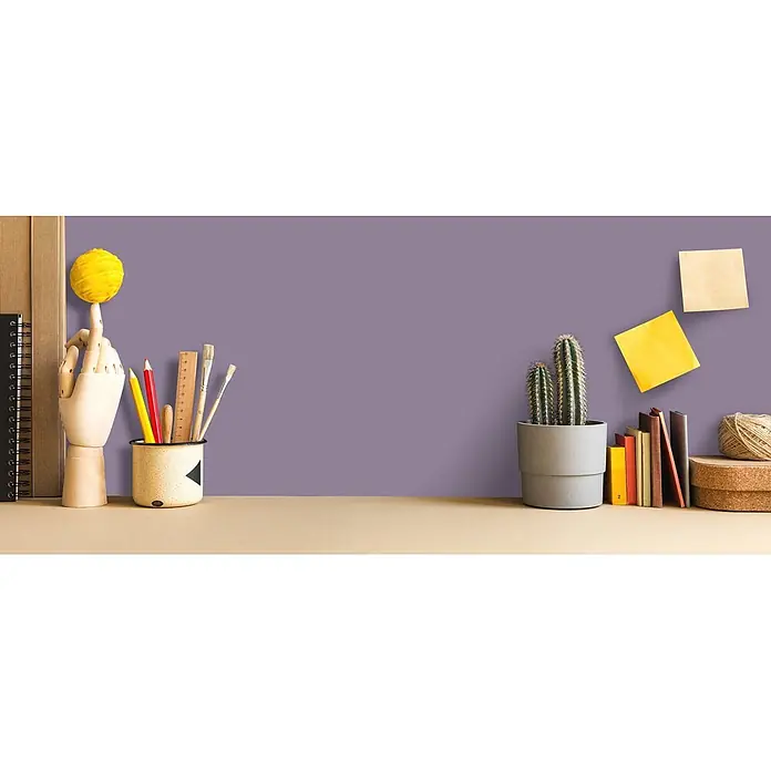 Tadessi Wandfarbe Dunkellavendel - Lila, Matt, 5 l - Kreativer Schreibtisch mit Holzhand, Kunstbedarf, Kaktus und Büchern vor violetter Wand.