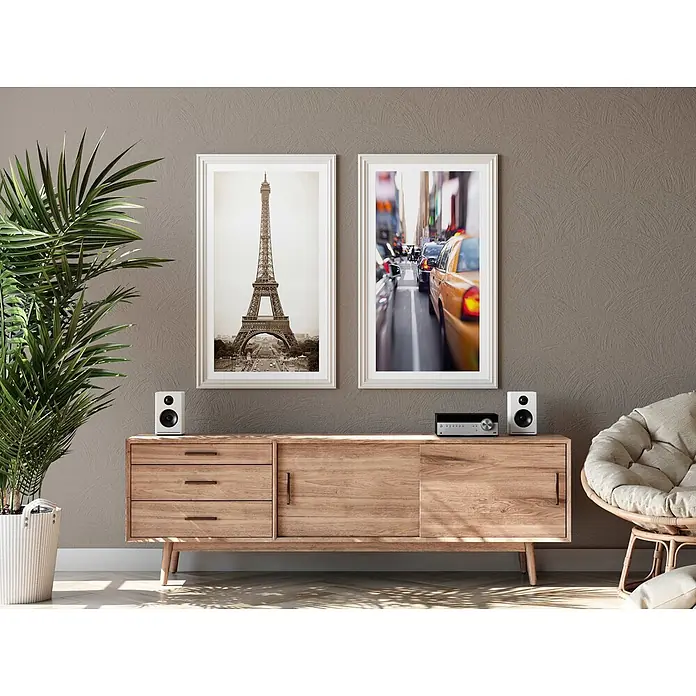 Tadessi Wandfarbe Kaffeecreme Mocha - Taupe, Matt, 5 l - Helle Holz-Medienkonsole mit Schubladen und Schränken, obenauf Lautsprecher und Receiver, in einem modernen Wohnzimmer.