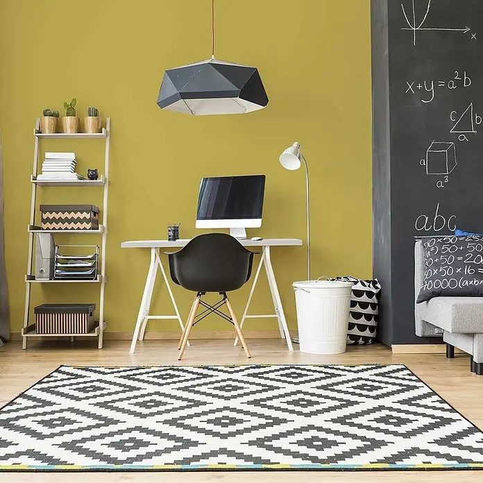 Tadessi Wandfarbe Weizengelb - Grün, Matt, 2,5 l - Ein großer schwarz-weiß gemusterter Teppich mit geometrischem Muster bedeckt den Boden in einem modernen Heimbüro.