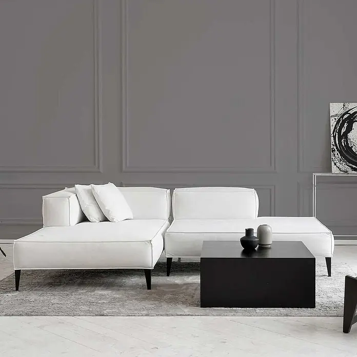 Tadessi Wandfarbe Dunkelgrau - Grau, Matt, 1 l - Ein modernes Wohnzimmer zeigt ein weißes Modulsofa mit Kissen und einen niedrigen rechteckigen schwarzen Couchtisch auf einem grauen Teppich.