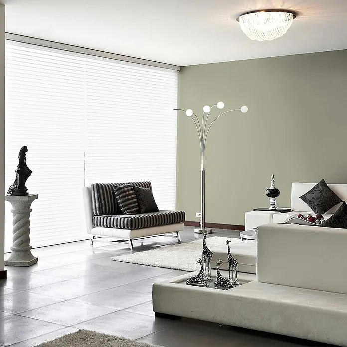 Tadessi Wandfarbe Helles Salbei - Grün, Matt, 2,5 l - Ein modernes Wohnzimmer mit einer hellgrünen Wand, weißen Jalousien, eleganten Sofas und einer modernen Stehleuchte.