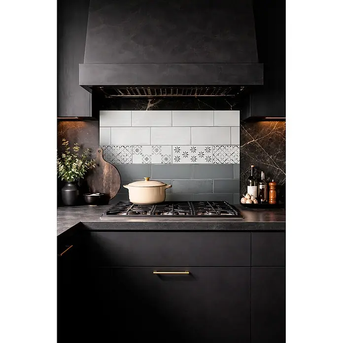 Protector de pared de cocina Cenefa - L x An x Es: 90 cm x 60 cm x 3 mm, Azul, Aluminio - Salpicadero de cocina con azulejos cerámicos blancos, estampados y grises instalados sobre una estufa de gas en una cocina oscura moderna.