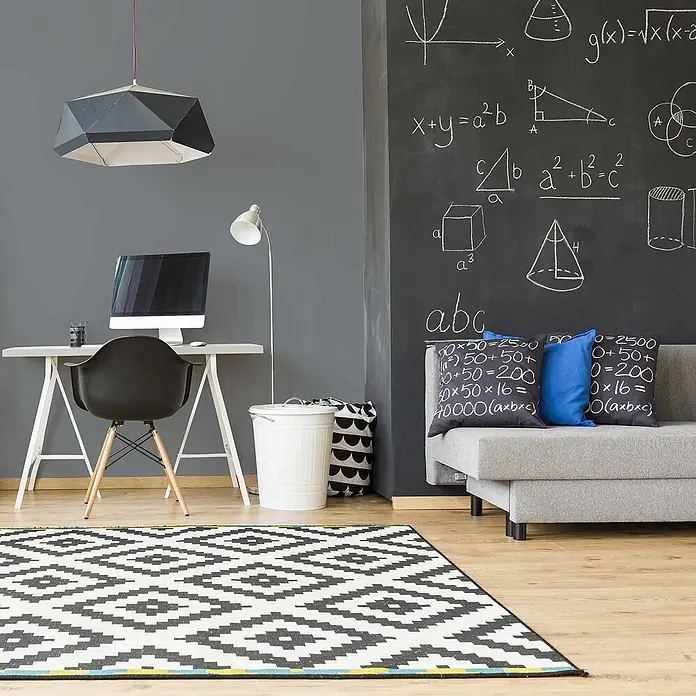 Tadessi Wandfarbe Blaugrau - Grau, Matt, 1 l - Ein schwarz-weißer Teppich mit geometrischem Muster auf Holzboden in einem modernen Raum, der einen stilvollen Akzent setzt.