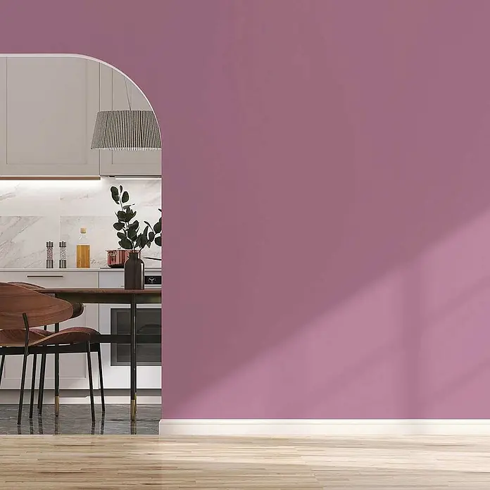 Tadessi Wandfarbe Himbeer - Pink, Matt, 5 l - Modernes Rauminterieur mit einer leuchtend violetten Wand im Vordergrund und einer stilvollen Küche durch einen Bogen sichtbar.