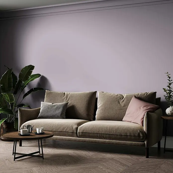 Tadessi Wandfarbe Lavendel - Violett, Matt, 1 l - Beiges Stoffsofa in einem modernen Wohnzimmer mit violetter Wand, Couchtisch und Pflanzen.